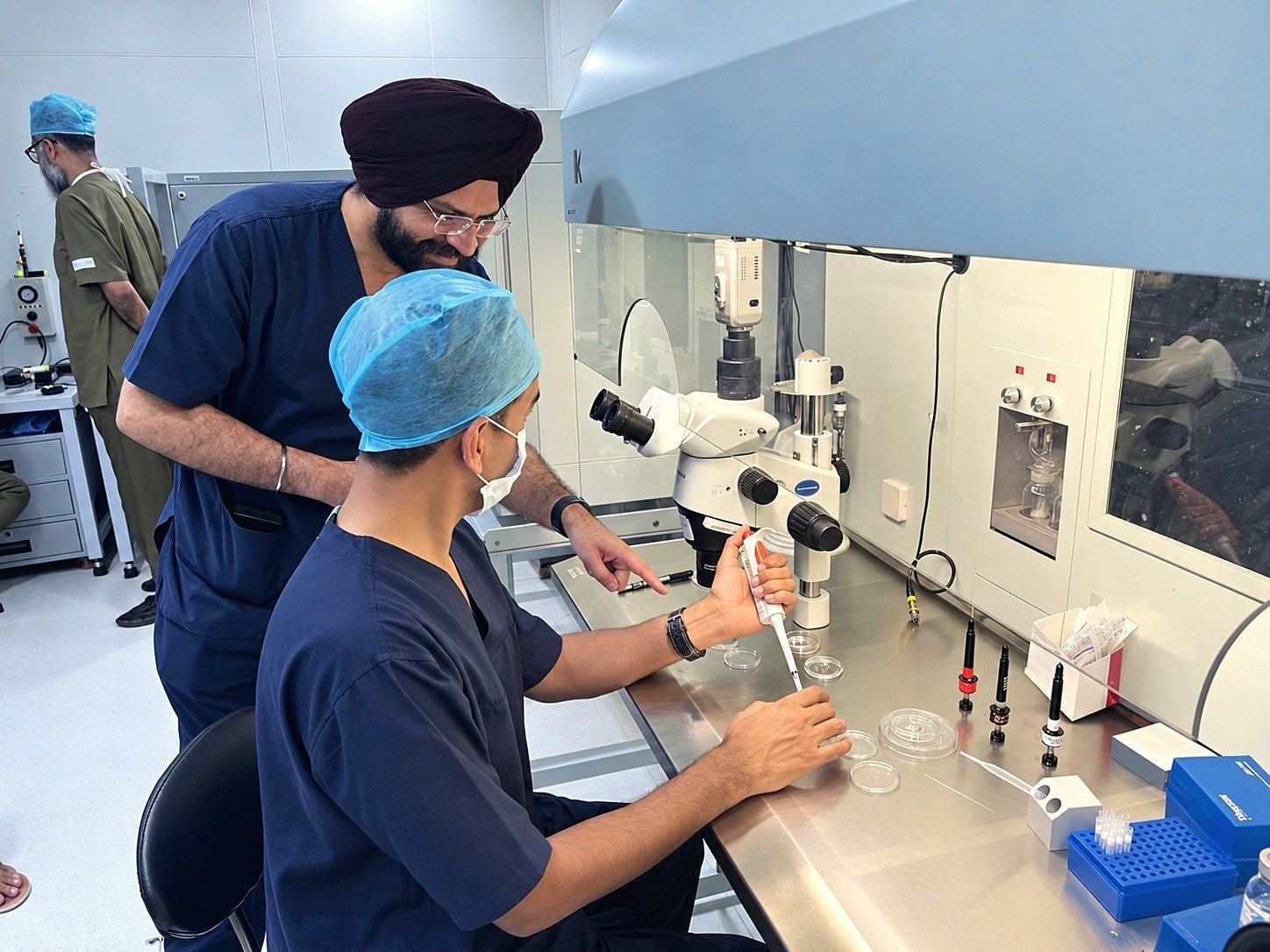 Dr. Sarabpreet Singh guides a trainee pipetting at an IVF lab workstation